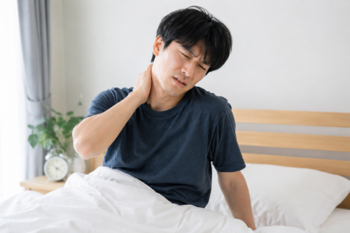 起床時に首の痛みを感じる男性の画像